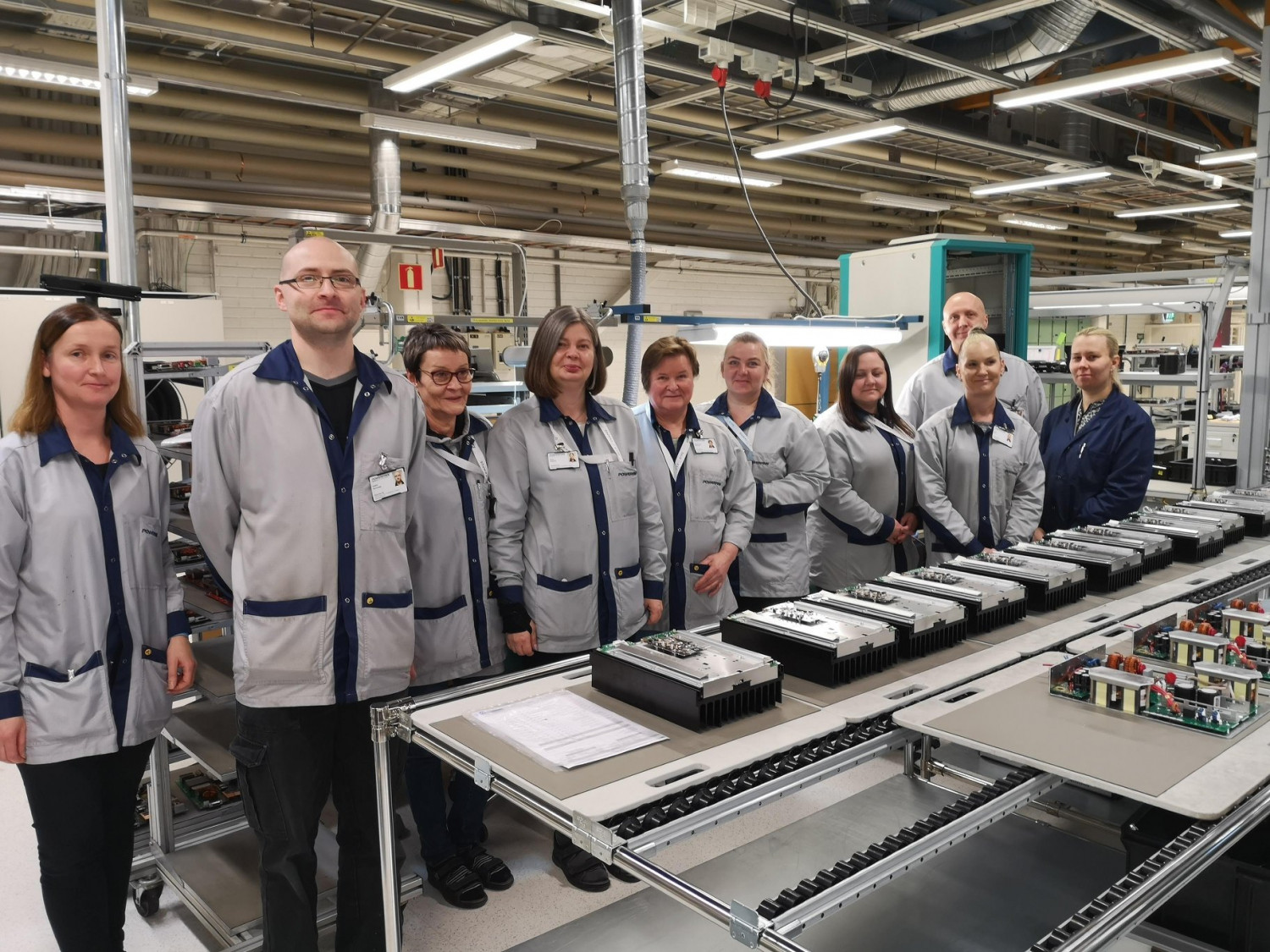 Ten employees at Micropower Group in Växjö, lined up and dressed in grey jackets and dark trousers.