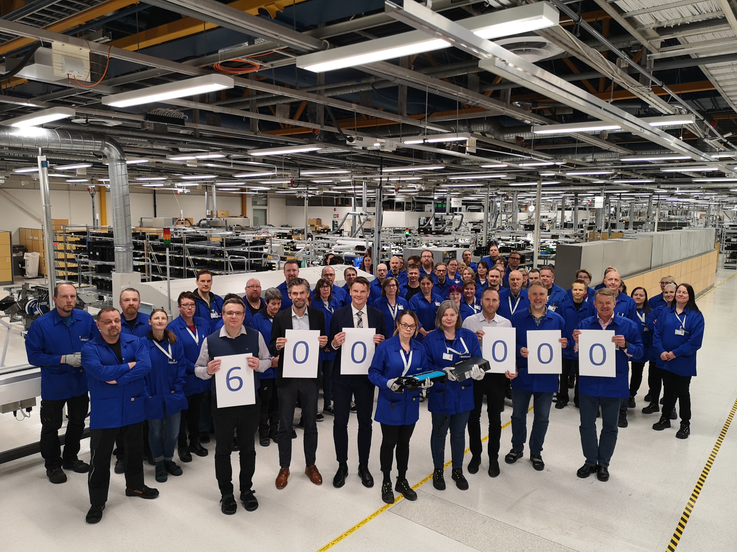 Employees at Micropower stand together in the factory and celebrate